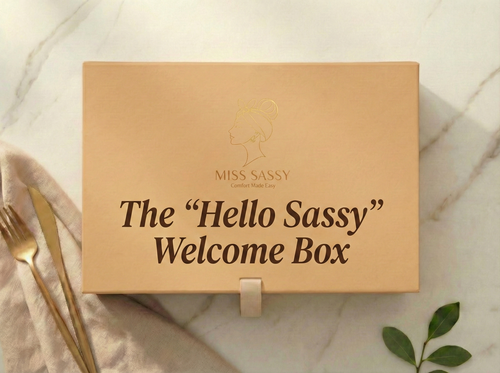 Brown box labeled 'The Hello Sassy Welcome Box' on a marble surface with a fork and leaf.